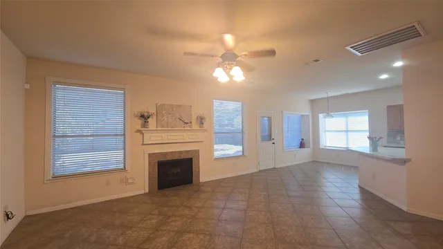 a view of a livingroom with a fireplace a ceiling fan and windows