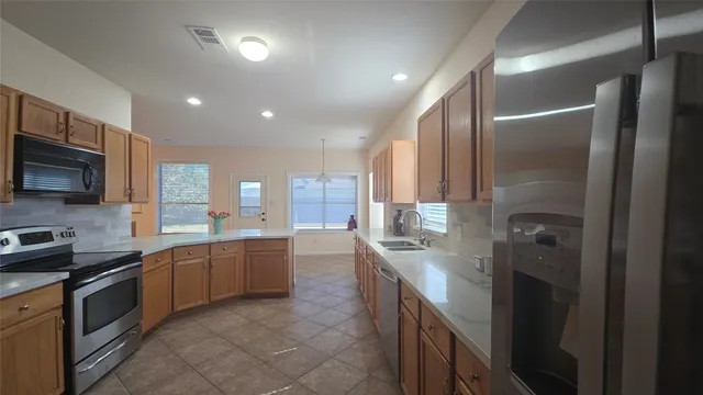 a large kitchen with stainless steel appliances granite countertop a sink and dishwasher a stove top oven with wooden floor