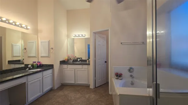 a spacious bathroom with a granite countertop sink a toilet a mirror and shower