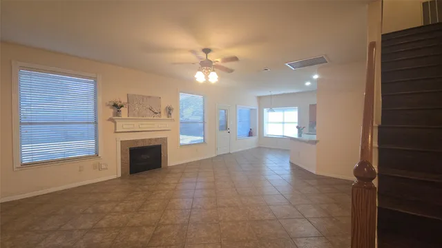 a view of a livingroom with a fireplace a ceiling fan and windows