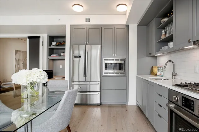 a kitchen with stainless steel appliances granite countertop a refrigerator a stove and a wooden floors