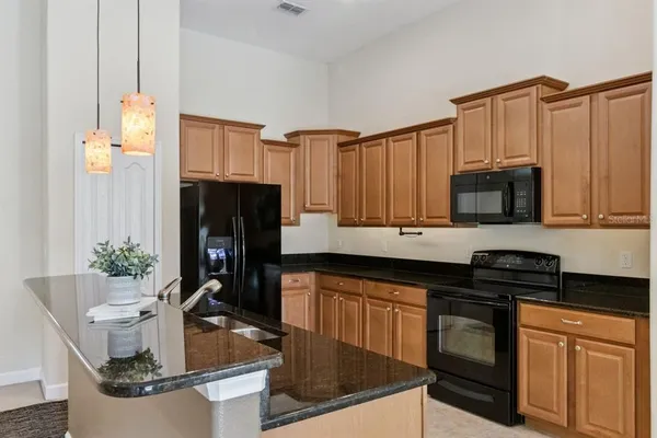 a kitchen with granite countertop a refrigerator stove and sink