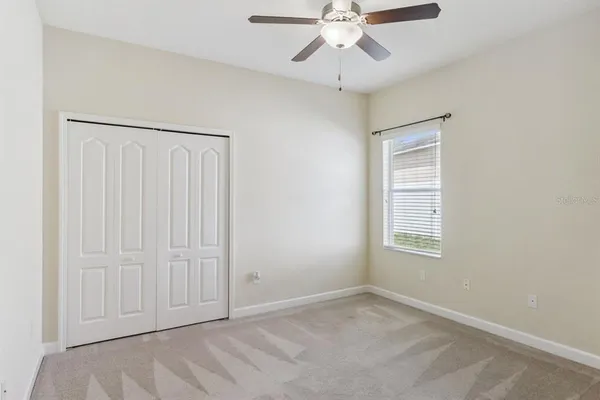 an empty room with a ceiling fan and a window