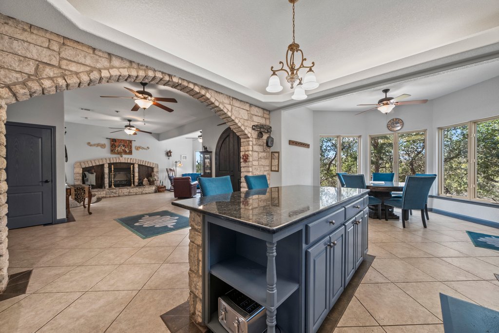 209 Lakeview Circle Spring Branch, TX 78070 - Photo 8 of 40 Kitchen with arched walkways, light tile patterned flooring, blue cabinetry, a center island, and open shelves