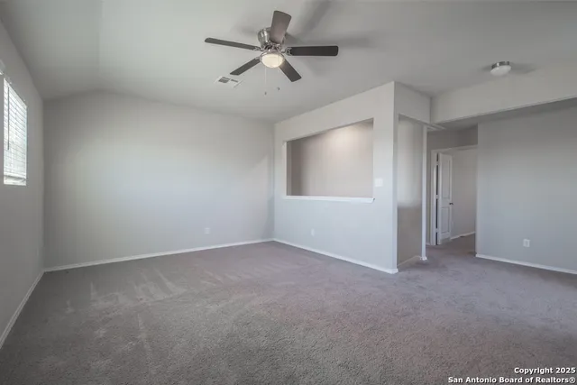 an empty room with fan and windows