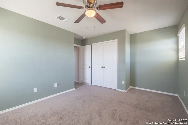 a view of an empty room and chandelier fan