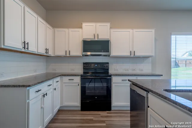 a kitchen with stainless steel appliances granite countertop a stove a sink and a microwave