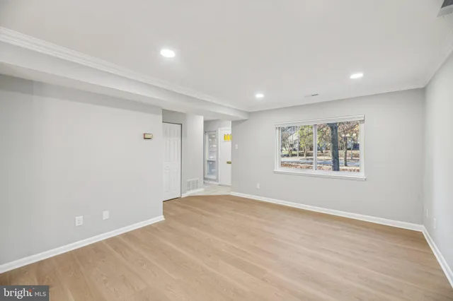 a view of an empty room with window and wooden floor