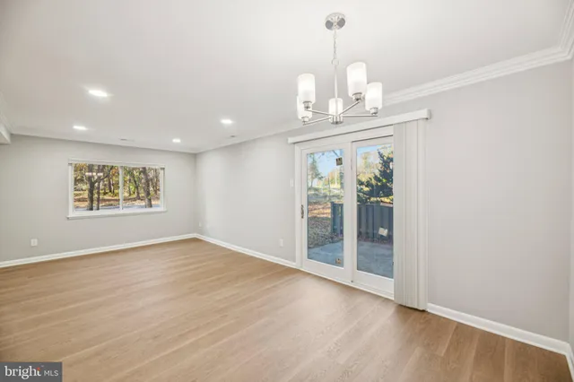an empty room with wooden floor chandelier and windows
