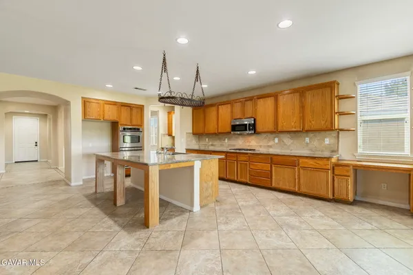 a large kitchen with granite countertop a large counter top space appliances and cabinets