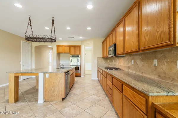 a large kitchen with stainless steel appliances granite countertop a stove a sink and a refrigerator