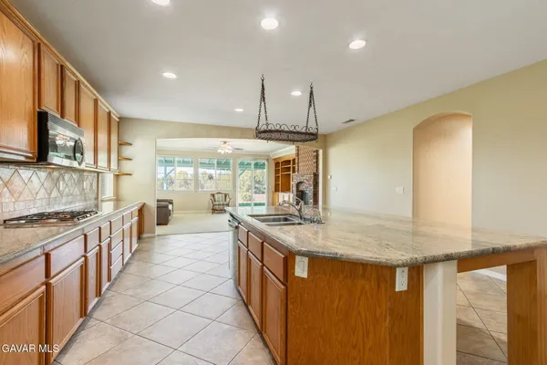 a kitchen with stainless steel appliances granite countertop a sink a stove and a wooden cabinets