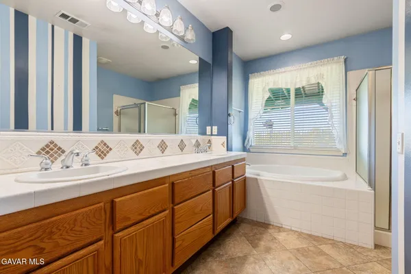 a bathroom with a bathtub double vanity sink and mirror