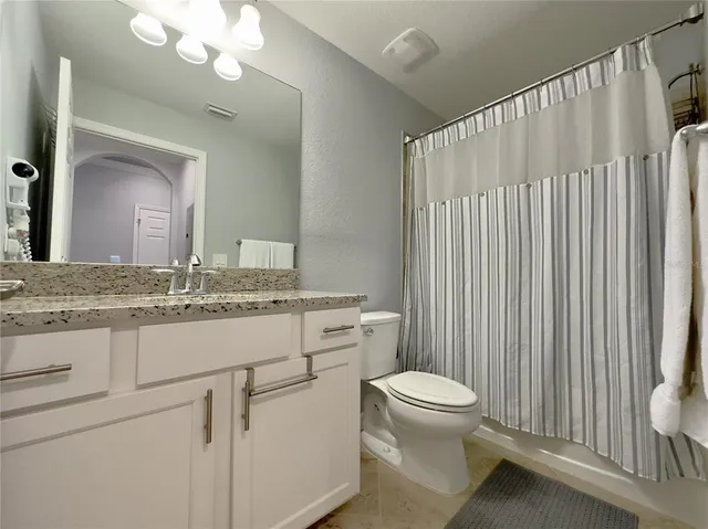 a bathroom with a granite countertop sink vanity mirror and toilet