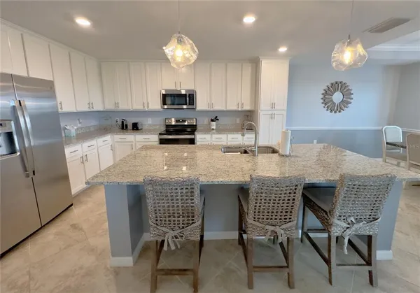 a kitchen with stainless steel appliances a dining table chairs microwave and sink