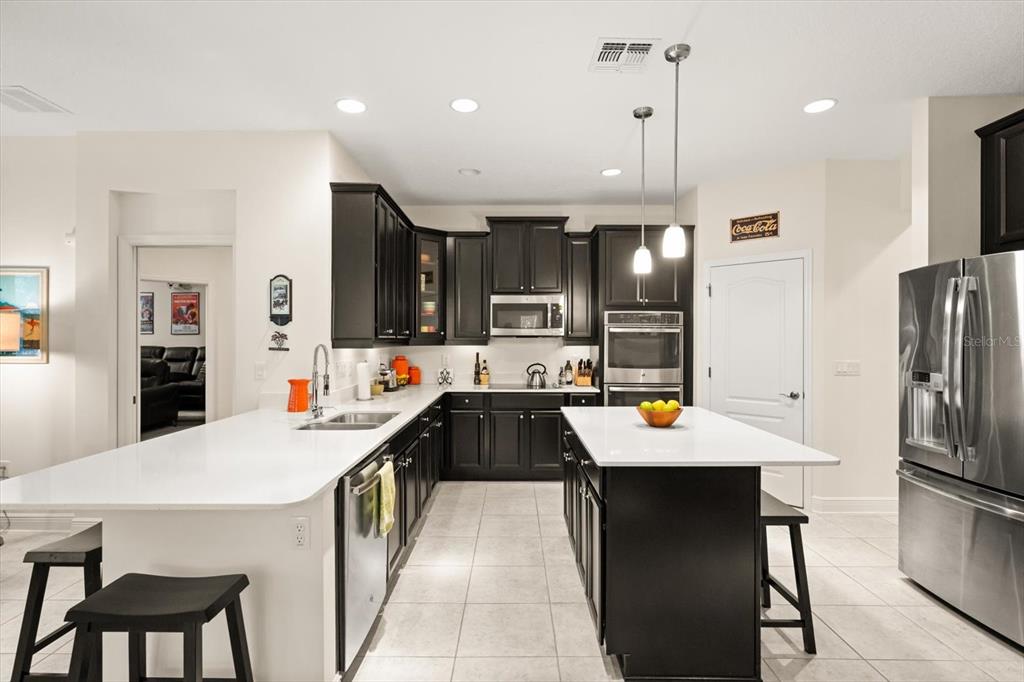 2709 Tree Meadow Loop Apopka, FL 32712 - Photo 2 of 31 a kitchen with stainless steel appliances kitchen island granite countertop a refrigerator a oven a sink a stove and chairs with wooden floor