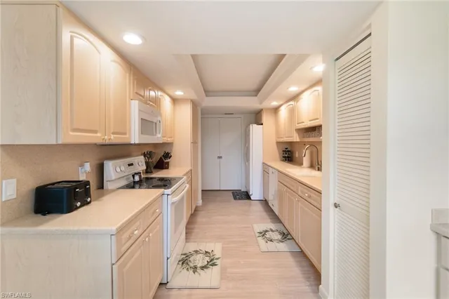 a kitchen with a sink a stove top oven and white cabinets