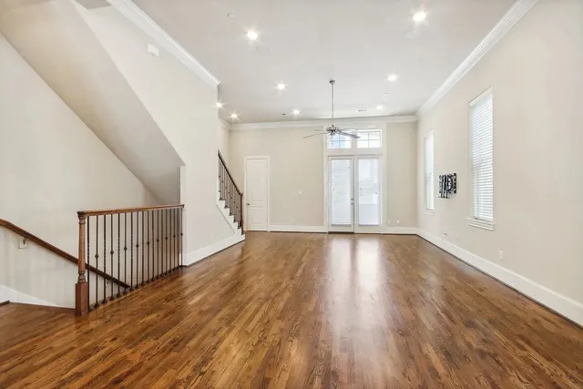 a view of an empty room with wooden floor and stairs