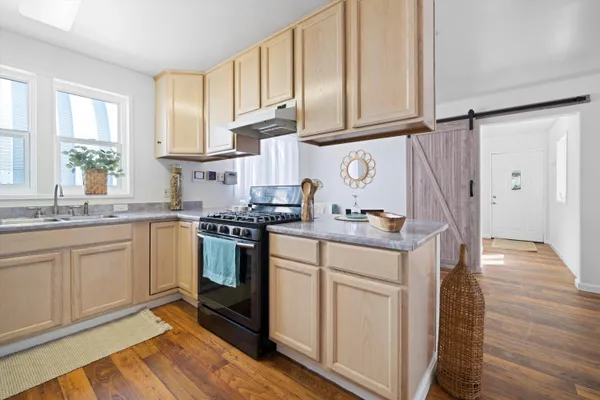 a kitchen with granite countertop a sink cabinets stainless steel appliances and a window