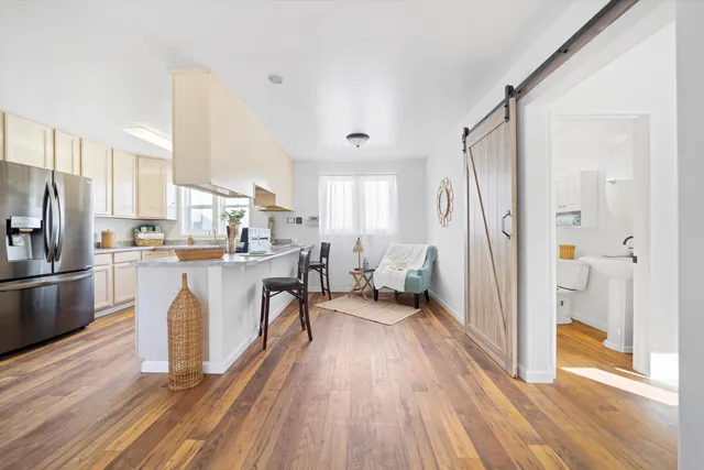 a kitchen with stainless steel appliances a refrigerator a stove a sink and white cabinets with wooden floor