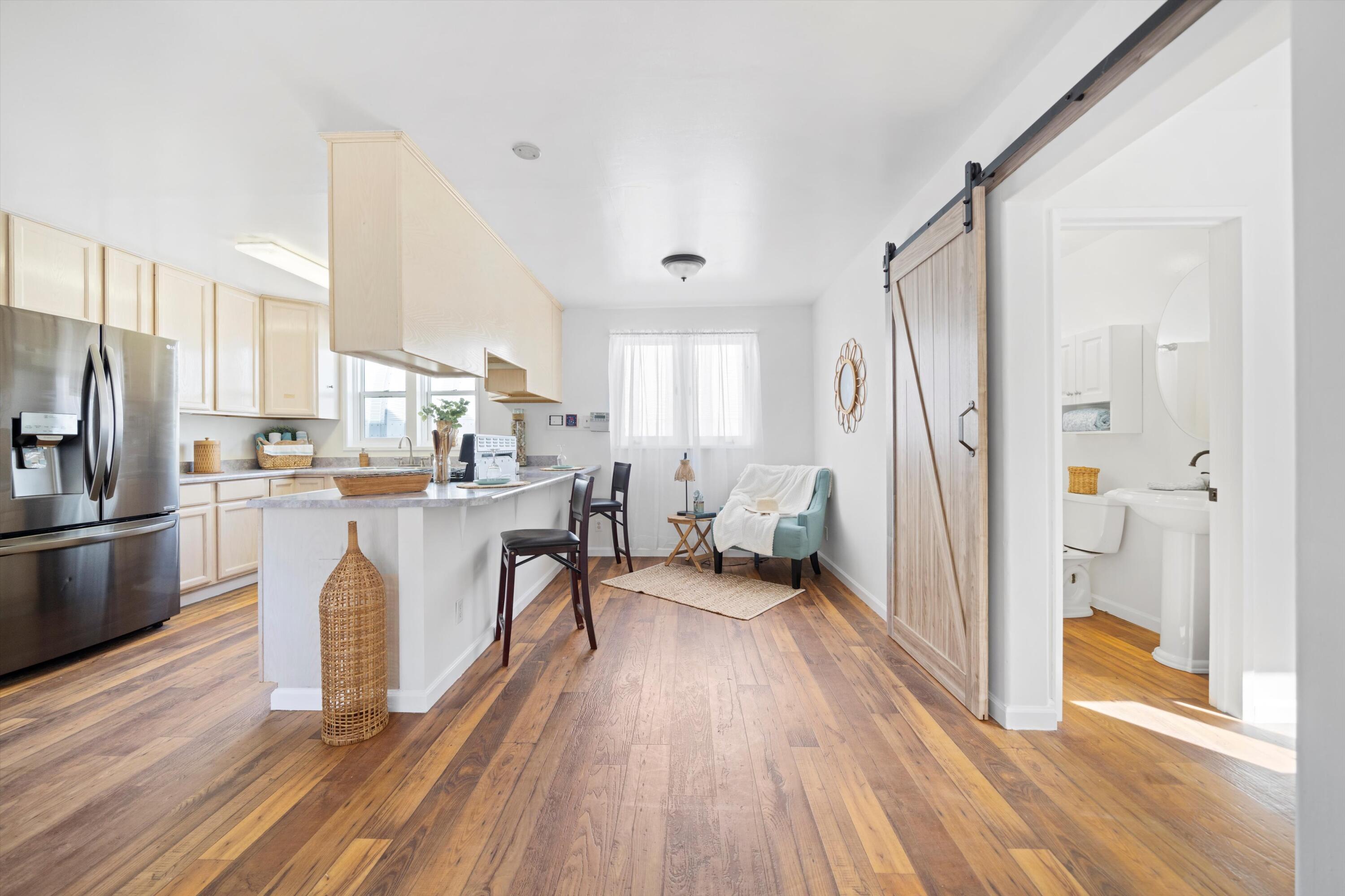 16930 Grindelwald Drive Tehachapi, CA 93561 - Photo 8 of 45 a kitchen with stainless steel appliances a refrigerator a stove a sink and white cabinets with wooden floor
