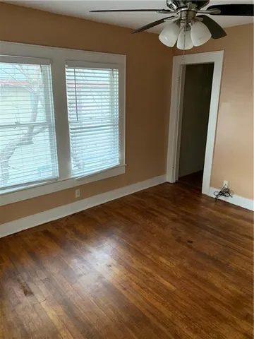 a view of an empty room with a window and wooden floor