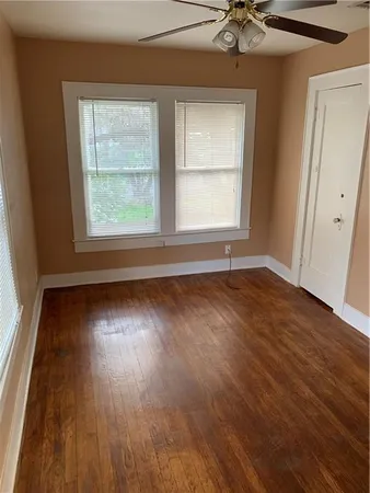 a view of an empty room with a window and wooden floor