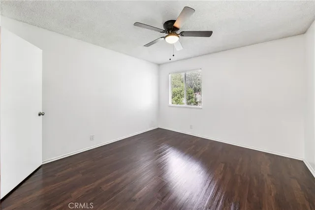 an empty room with wooden floor ceiling fan and windows