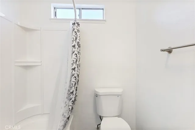 a view of a hallway with wooden floor and a bathroom