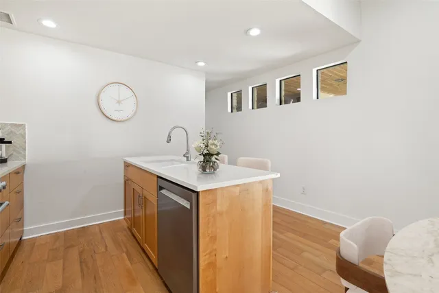 a kitchen with stainless steel appliances granite countertop a stove a refrigerator a oven a sink a dining table and chairs with wooden floor