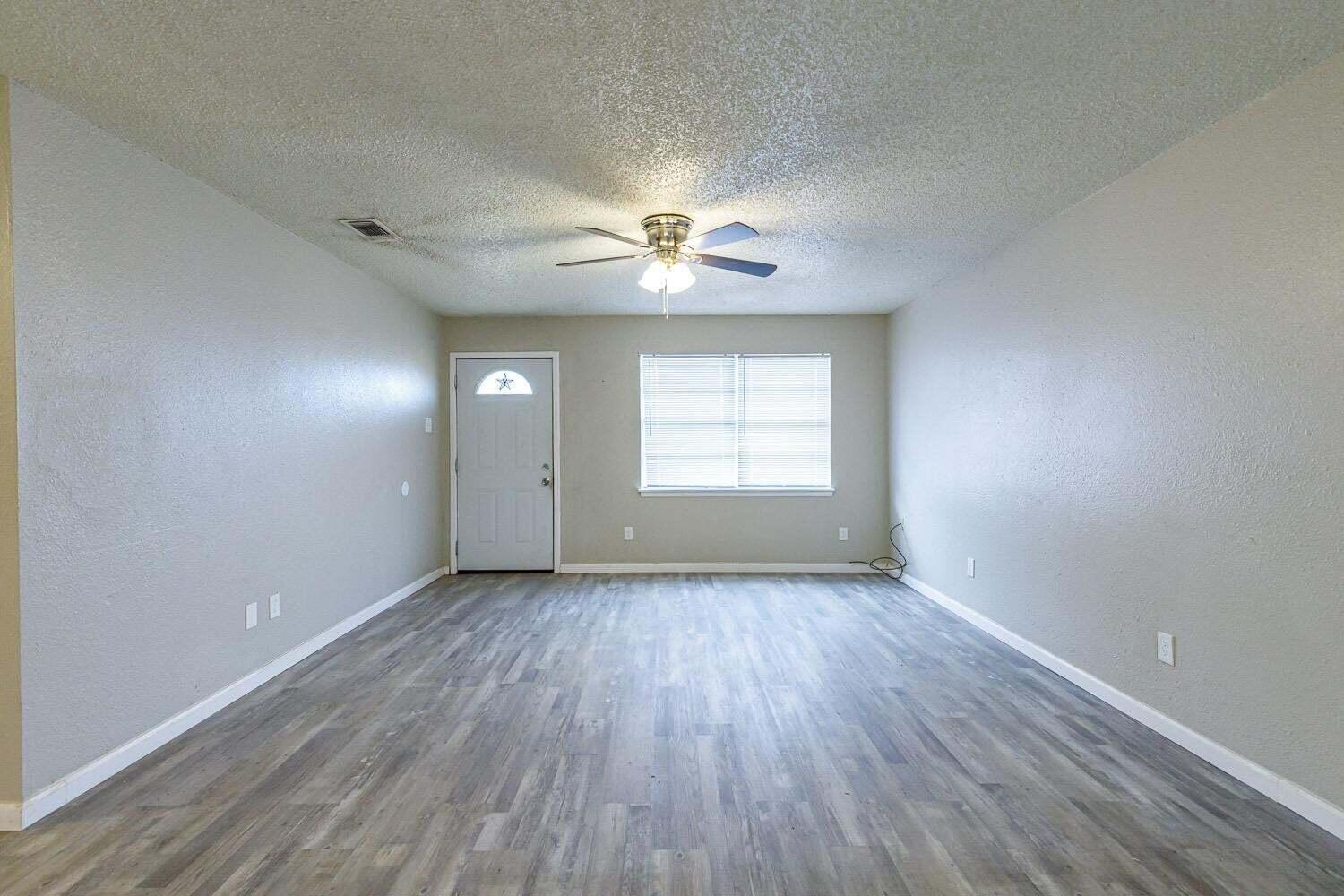 4634 Fordham Street Lubbock, TX 79416 - Photo 2 of 13 an empty room with chandelier fan and windows