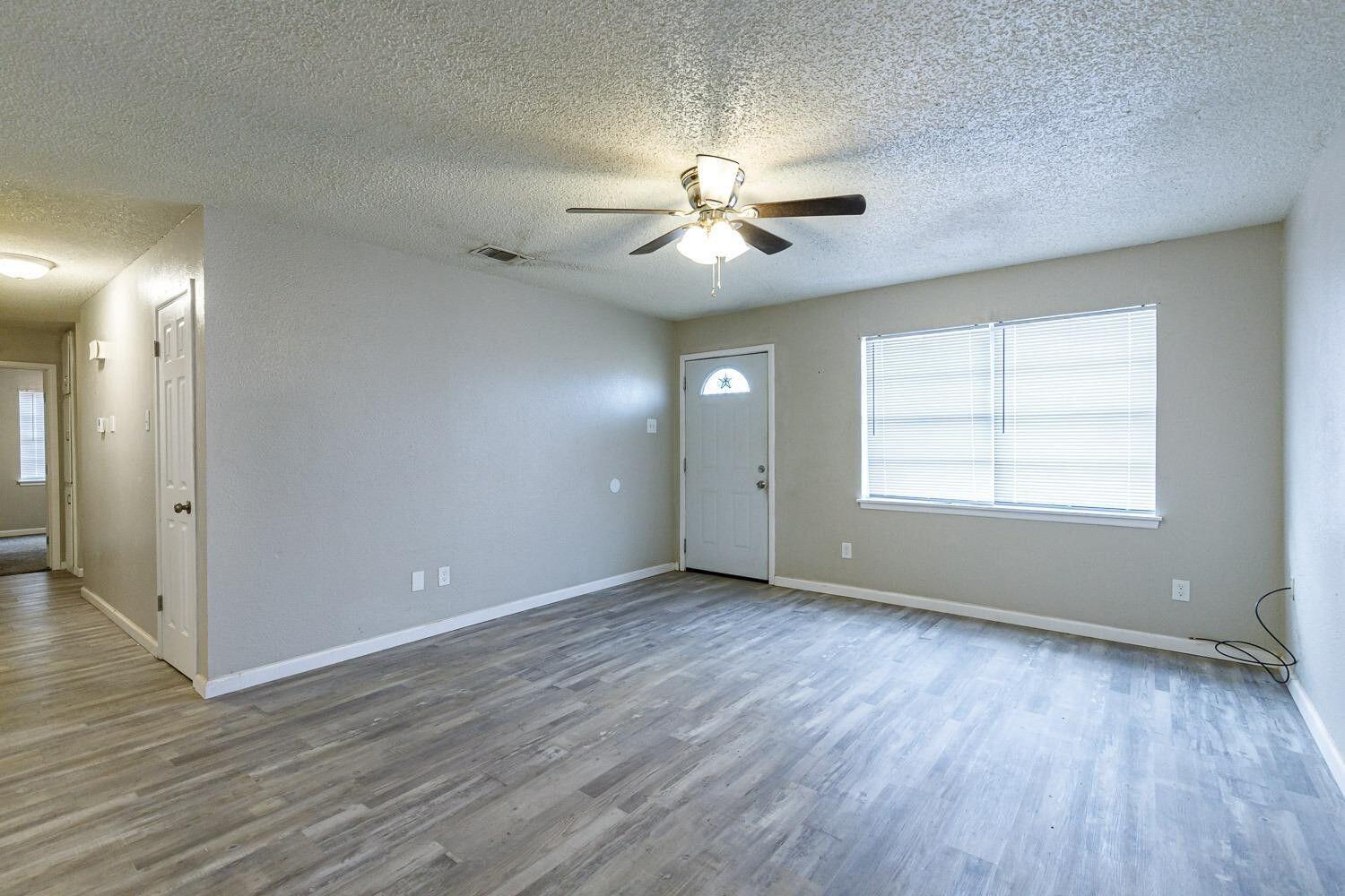 4634 Fordham Street Lubbock, TX 79416 - Photo 3 of 13 wooden floor in an empty room with a window