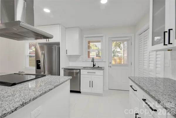 a large kitchen with granite countertop a sink and a stove