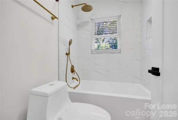 a bathroom with a bath tub a toilet and a window