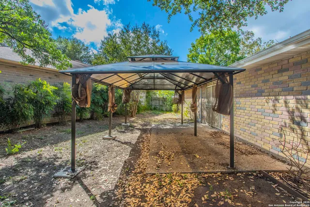 a view of a patio with a table and chairs under an umbrella with a small yard