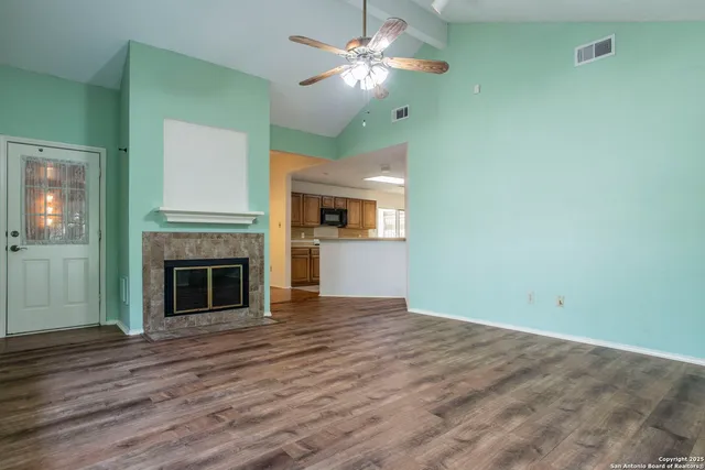 a view of a kitchen with a fireplace a ceiling fan and wooden floor