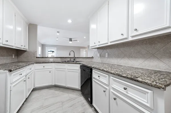 a kitchen with granite countertop white cabinets and white appliances