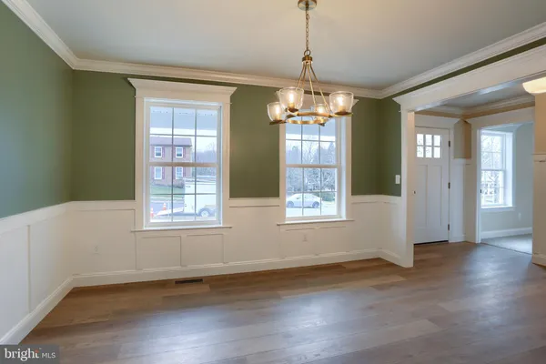 a view of a room with wooden floor chandelier and windows