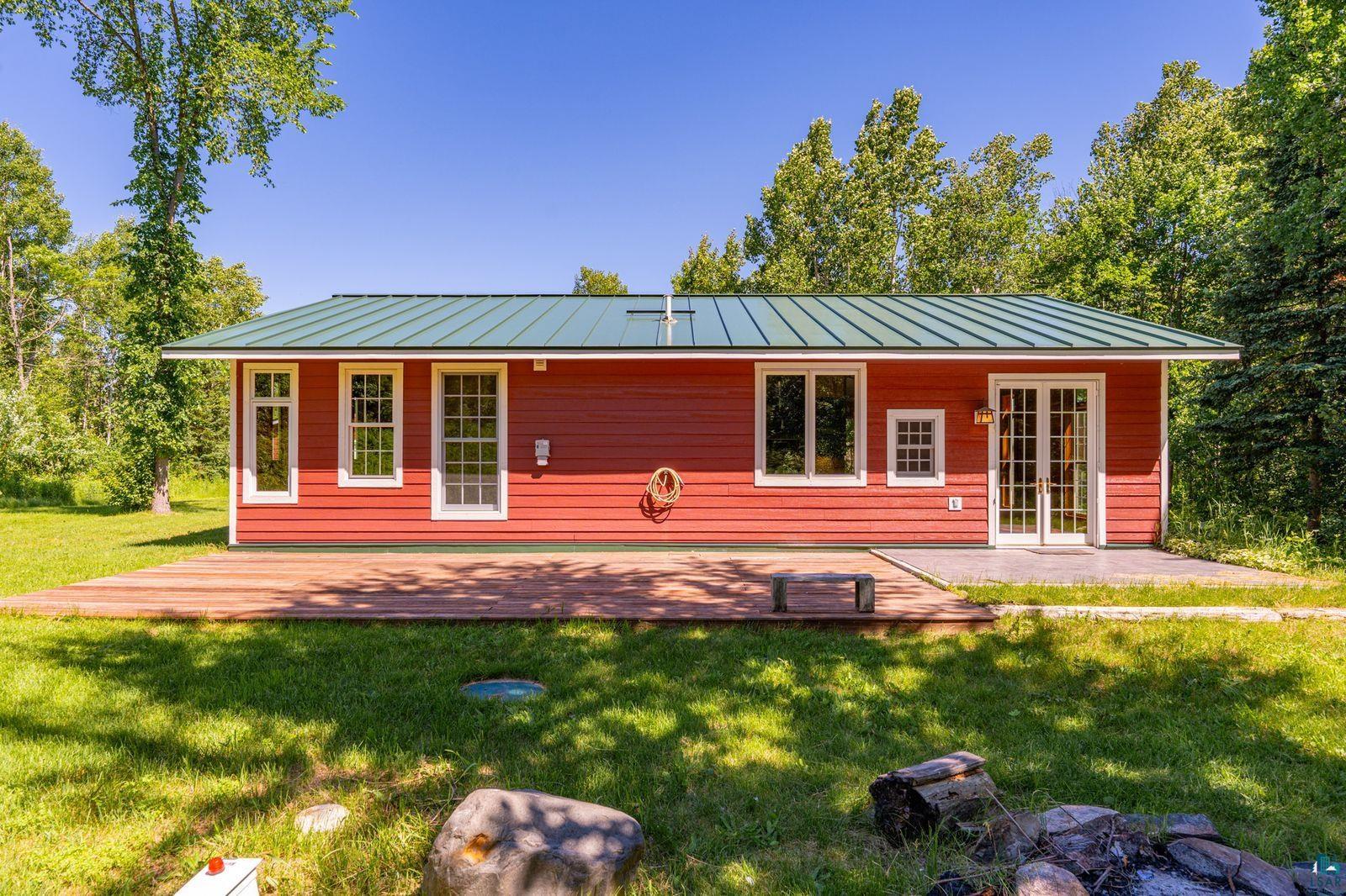 9734 Alango Road Angora, MN 55703 - Photo 25 of 41 Red-sided residence featuring a green metal roof and a spacious wooden deck
