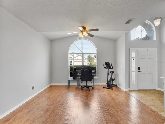 an empty room with wooden floor fan and windows