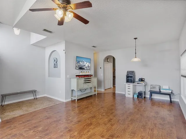 a view of a livingroom with a flat screen tv wooden floor and a ceiling fan