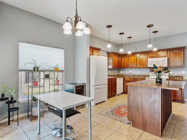 a kitchen with stainless steel appliances granite countertop a refrigerator a stove a sink dishwasher a dining table and chairs with wooden floor