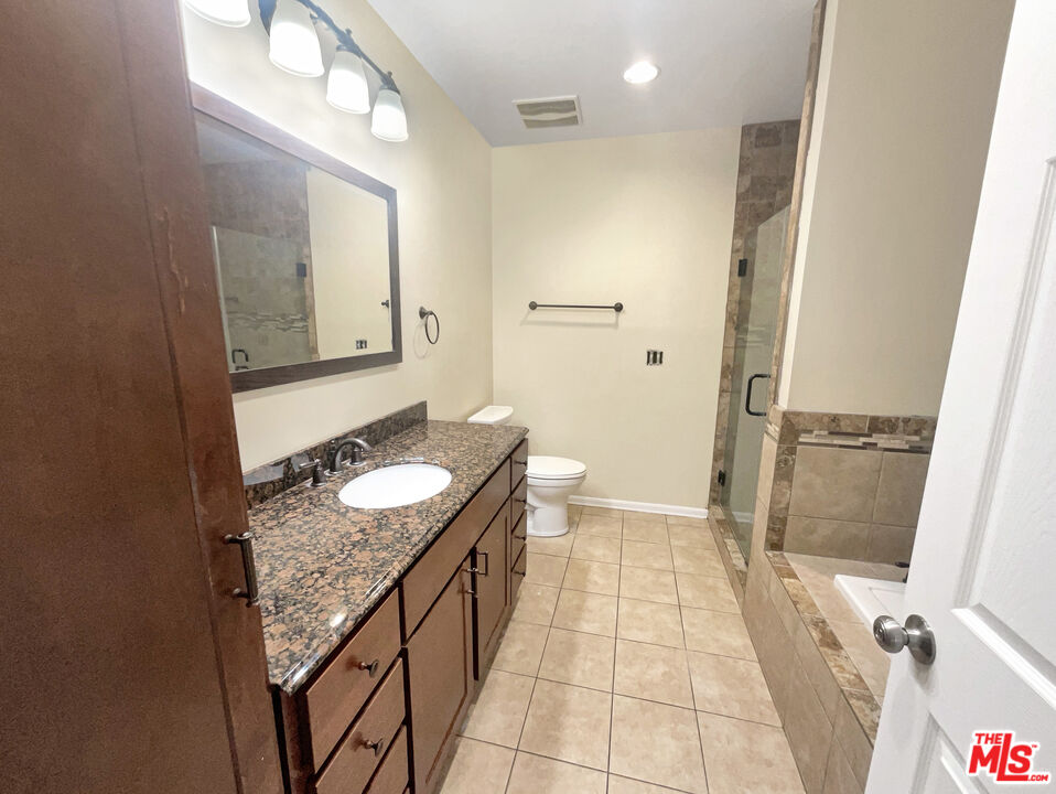 13242 Cornuta Avenue Downey, CA 90242 - Photo 13 of 19 a bathroom with a granite countertop sink a mirror and a shower