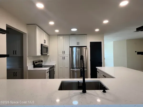 a large kitchen with stainless steel appliances a refrigerator and a sink