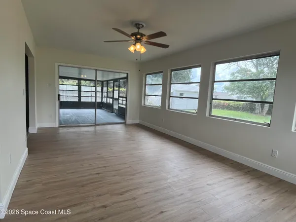 an empty room with wooden floor and windows