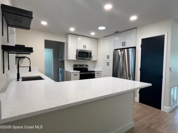 a large kitchen with stainless steel appliances a refrigerator and a stove top oven