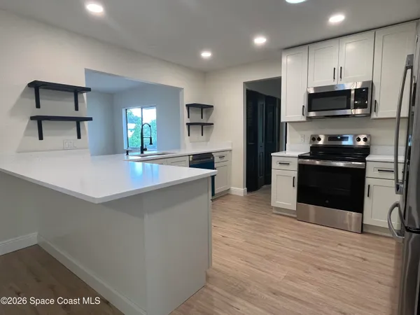 a large kitchen with stainless steel appliances a large counter top a stove a chimney a sink and a refrigerator
