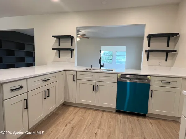 a kitchen with white cabinets sink and dishwasher with wooden floor