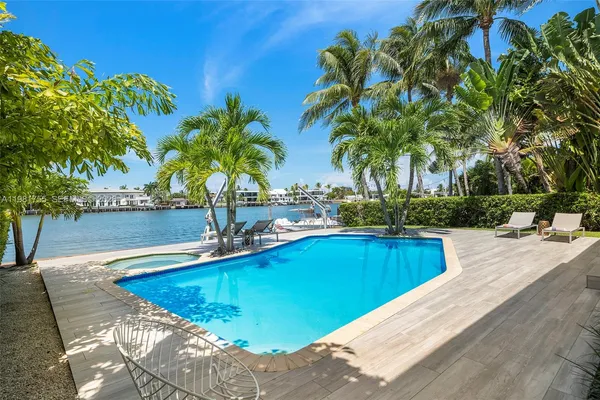 a view of a swimming pool with a yard and palm trees