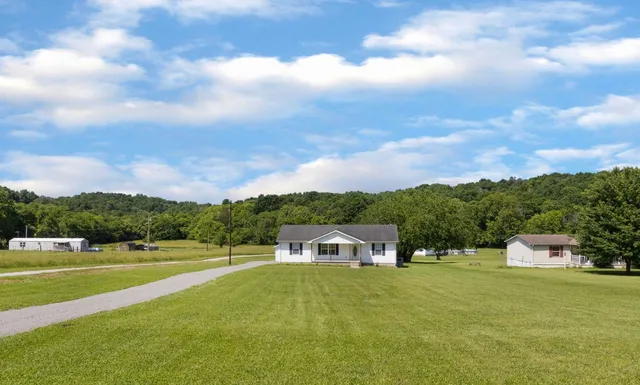 a view of a big house with a big yard and large trees